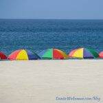 colorful umbrellas on a beach with ocean in the background