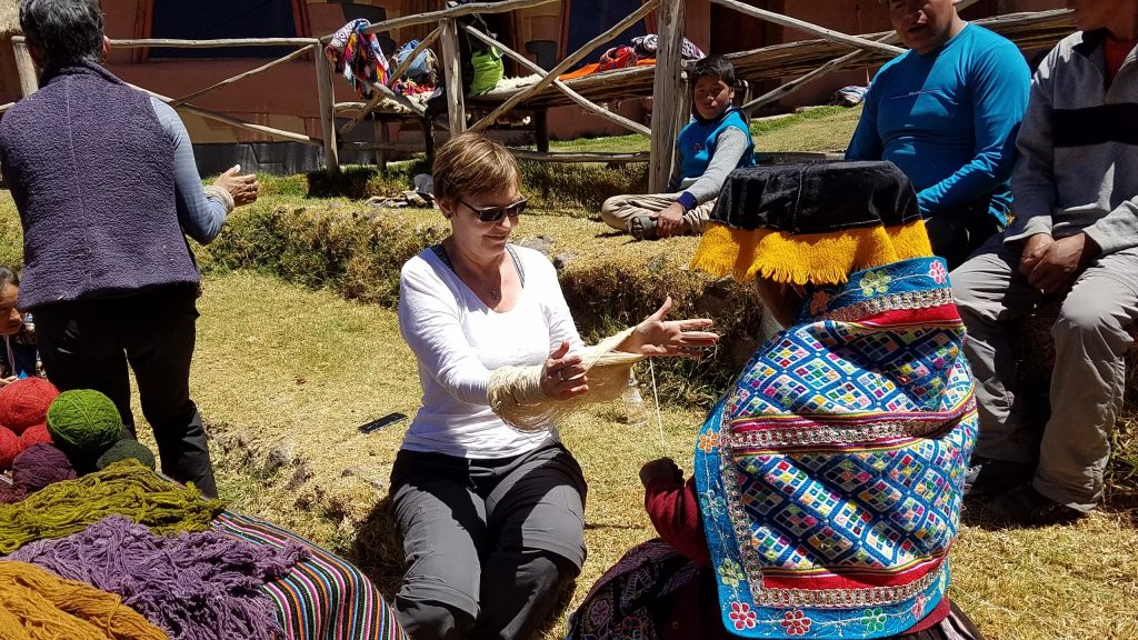 Denise helping woman spin wool in Peru