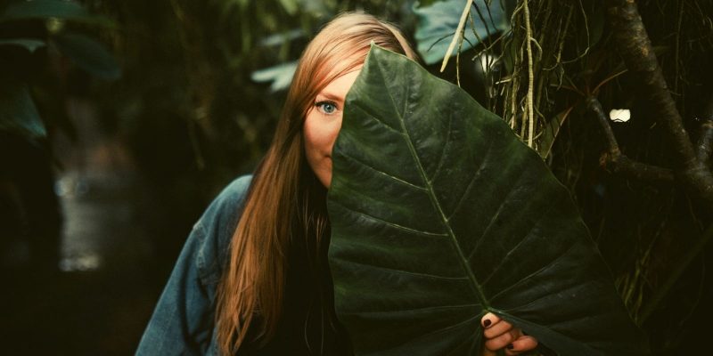 woman hiding behind a large leaf