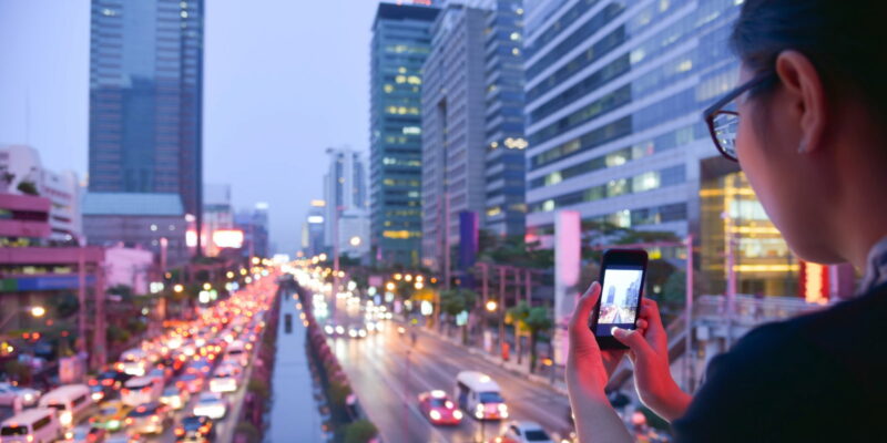 young woman looking out over streets with traffic and taking a picture